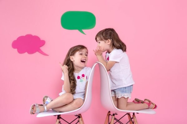 two-little-girls-colored-wall-with-speech-icons